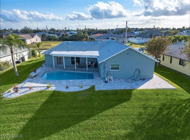 back of house with a fenced in pool, a patio area, and a lawn