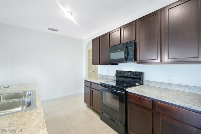 kitchen with dark brown cabinetry, sink, light tile patterned floors, and black appliances