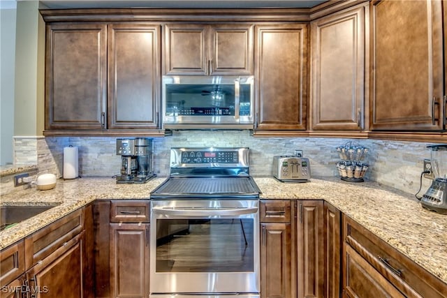 kitchen with stainless steel appliances, tasteful backsplash, and light stone countertops