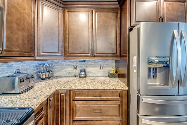 kitchen featuring tasteful backsplash, stainless steel fridge, and light stone counters