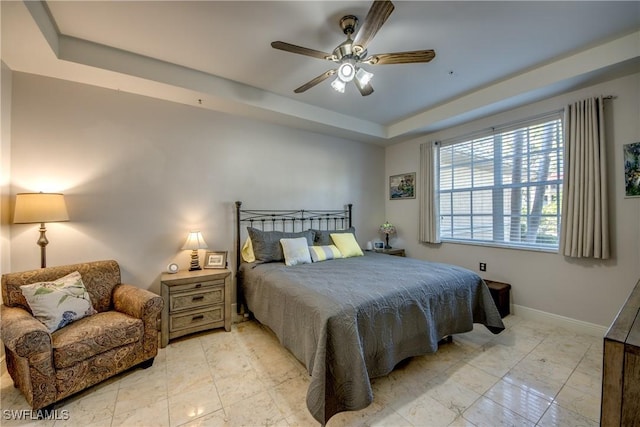 bedroom with ceiling fan and a tray ceiling