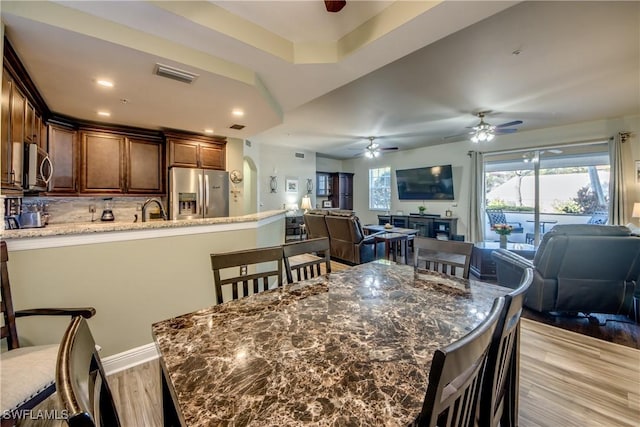 dining space featuring sink, light hardwood / wood-style flooring, and ceiling fan