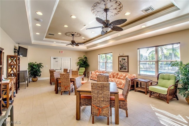 dining space with crown molding, ceiling fan, a raised ceiling, and light hardwood / wood-style flooring