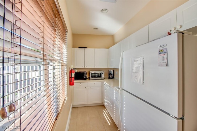 kitchen with white refrigerator, plenty of natural light, and white cabinets