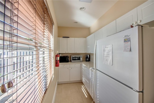 kitchen featuring white refrigerator and white cabinets