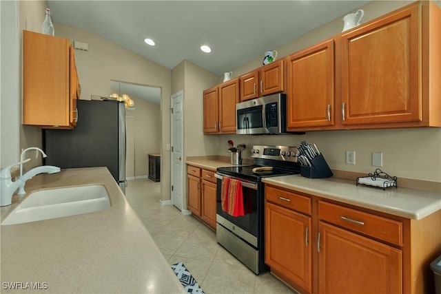 kitchen featuring lofted ceiling, appliances with stainless steel finishes, sink, and light tile patterned floors