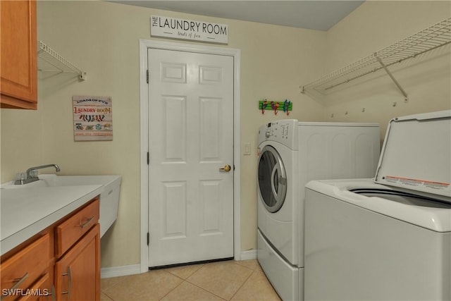 laundry room featuring washer and clothes dryer, cabinets, and light tile patterned flooring