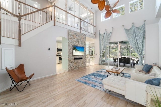 15881 Delasol Ln, Naples, FL 34110 - living area featuring a ceiling fan, a towering ceiling, arched walkways, a fireplace, and wood finished floors