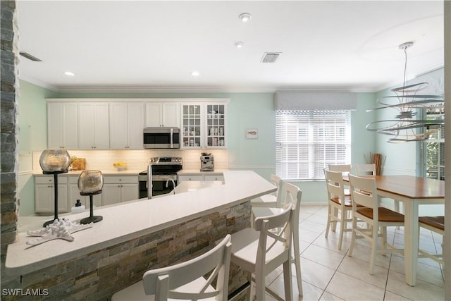 kitchen featuring stainless steel appliances, a kitchen breakfast bar, tasteful backsplash, visible vents, and pendant lighting