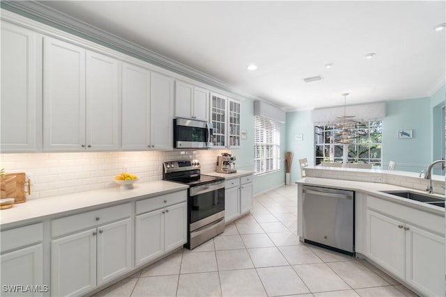 15881 Delasol Ln, Naples, FL 34110 - kitchen featuring appliances with stainless steel finishes, a sink, decorative backsplash, white cabinetry, and crown molding