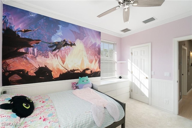 bedroom featuring light carpet, wainscoting, visible vents, ceiling fan, and crown molding