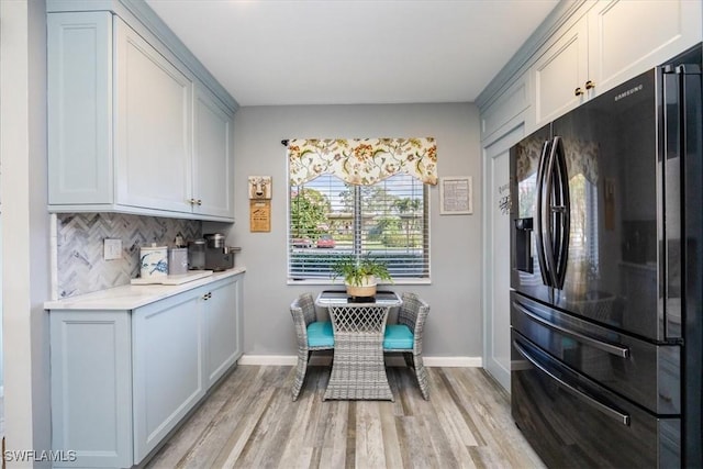 4572 Andover Way Unit C102, Naples, FL 34112 - kitchen with light countertops, baseboards, light wood-style floors, black refrigerator with ice dispenser, and backsplash