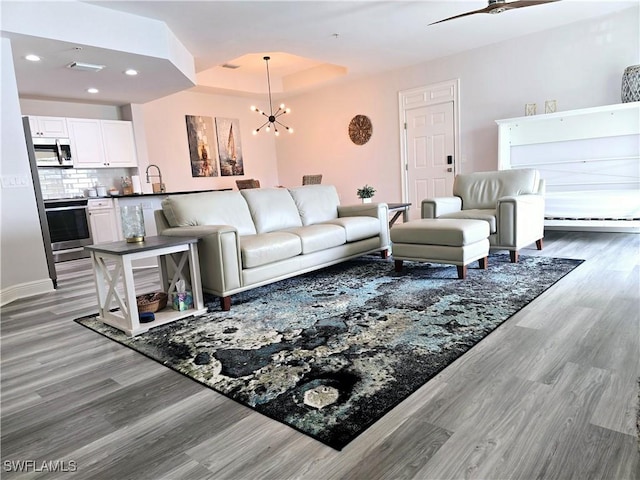 living room with a tray ceiling, dark hardwood / wood-style flooring, and a chandelier