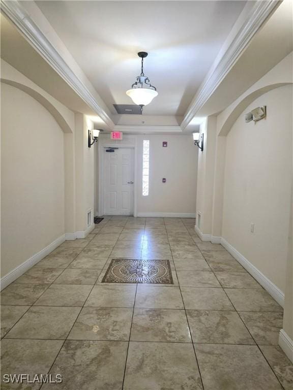 entryway with a raised ceiling, ornamental molding, and tile patterned floors