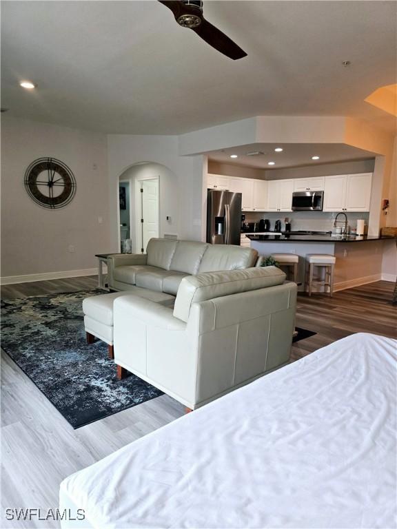 living room with dark hardwood / wood-style floors, sink, and ceiling fan