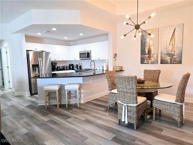 kitchen featuring stainless steel appliances, hardwood / wood-style floors, white cabinets, and kitchen peninsula