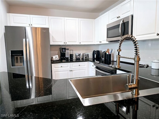 kitchen with stainless steel appliances, white cabinetry, and backsplash