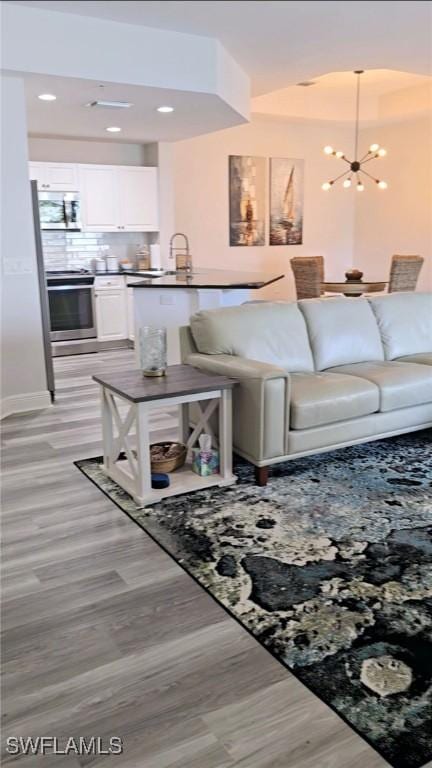 living room with sink, a chandelier, and light wood-type flooring