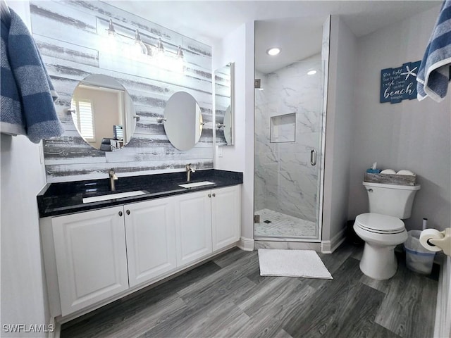 bathroom with wood-type flooring, toilet, an enclosed shower, and vanity