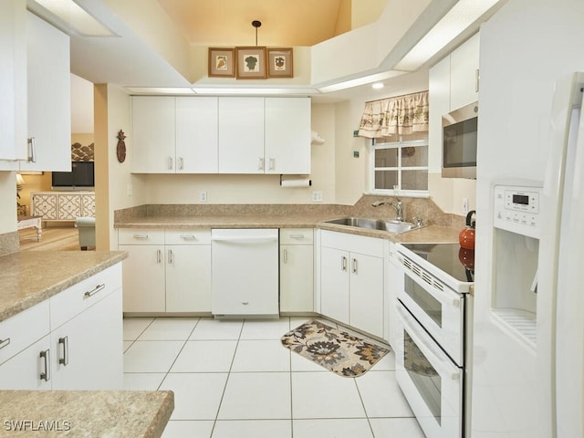 kitchen featuring sink, white appliances, light tile patterned floors, and white cabinets