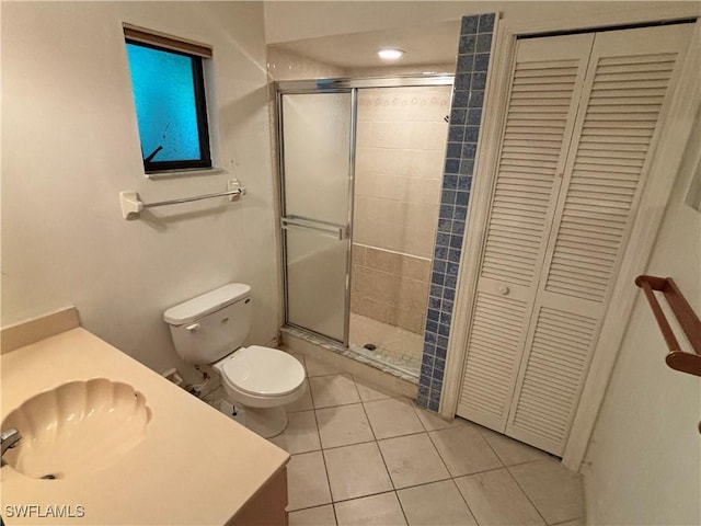 bathroom featuring tile patterned flooring, vanity, a shower with shower door, and toilet