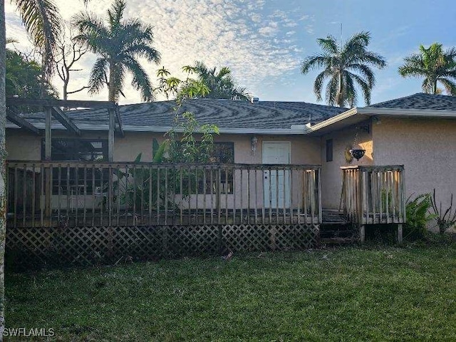 back house at dusk featuring a wooden deck and a lawn