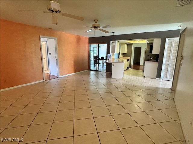 empty room with ceiling fan and light tile patterned floors