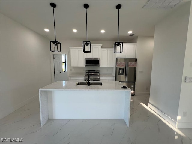 kitchen featuring appliances with stainless steel finishes, pendant lighting, white cabinets, light stone counters, and a center island with sink