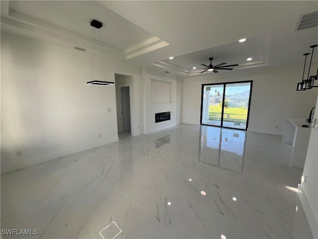 unfurnished living room with a raised ceiling and ceiling fan