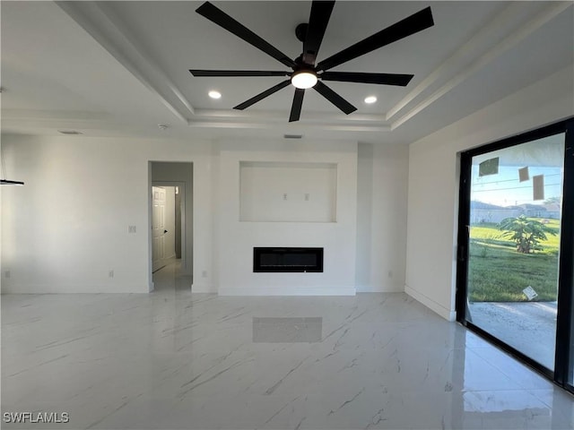 unfurnished living room featuring a raised ceiling and ceiling fan