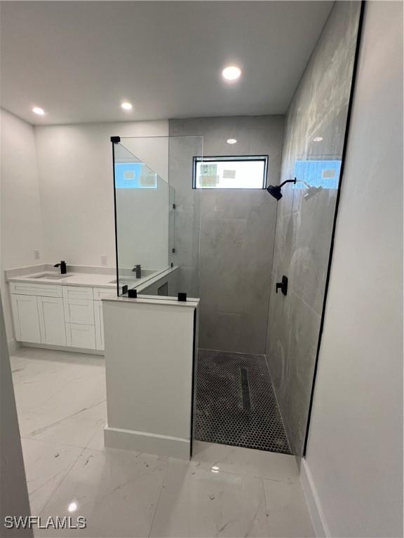 bathroom with a tile shower and vanity