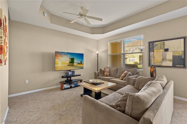 tiled living room featuring ceiling fan and a raised ceiling