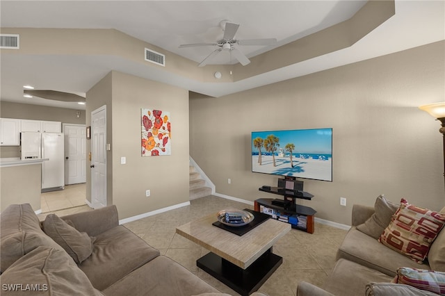 tiled living room featuring ceiling fan and a tray ceiling