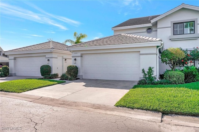 view of front of home featuring a garage, driveway, a tile roof, a front lawn, and stucco siding