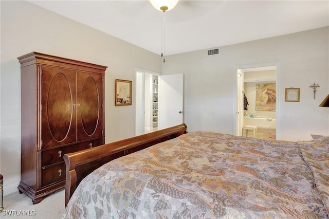 bedroom featuring ensuite bathroom, visible vents, and light colored carpet