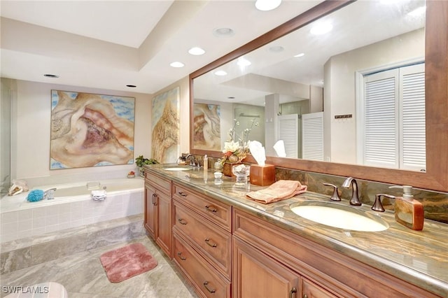 bathroom with a garden tub, double vanity, a sink, and recessed lighting