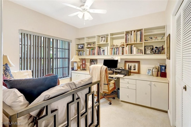 office space with built in study area, a ceiling fan, and light colored carpet