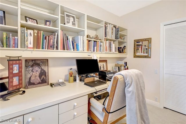 office area featuring light carpet, built in study area, and baseboards