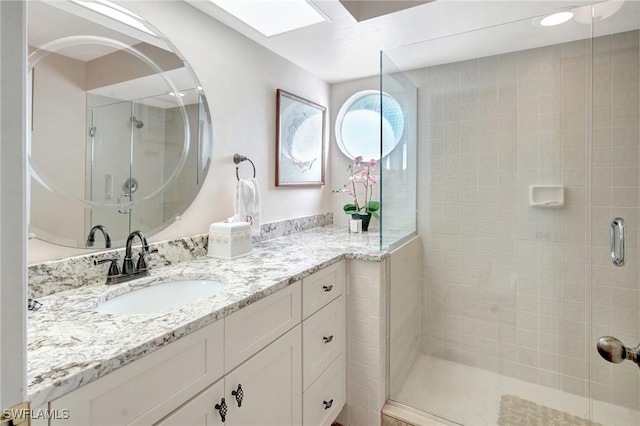 full bath featuring a stall shower, a skylight, and vanity