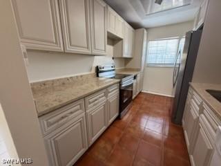 kitchen with dark tile patterned flooring, light stone countertops, and appliances with stainless steel finishes