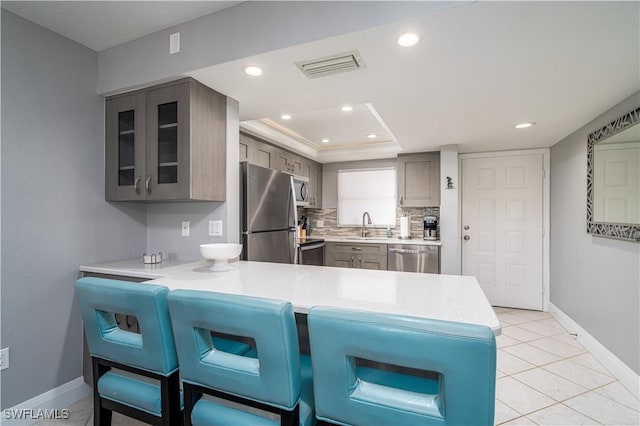 kitchen with appliances with stainless steel finishes, kitchen peninsula, sink, and decorative backsplash