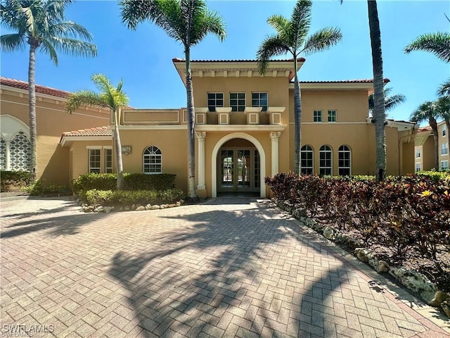 view of front facade with french doors, a tiled roof, and stucco siding