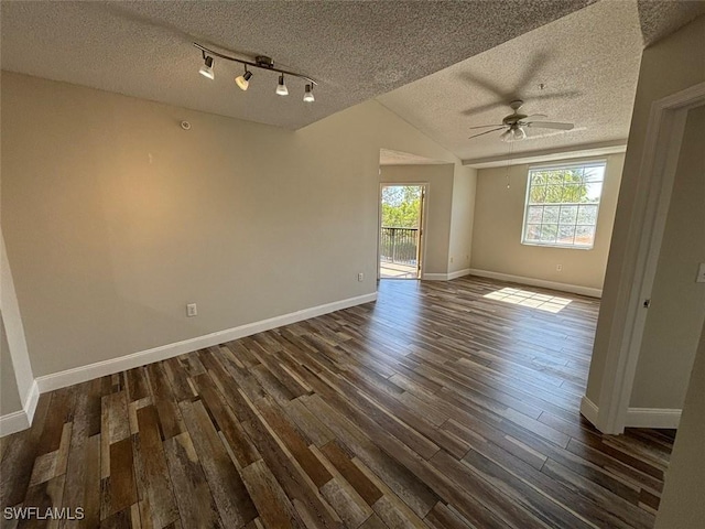 unfurnished room with a textured ceiling, dark wood-style floors, lofted ceiling, baseboards, and ceiling fan