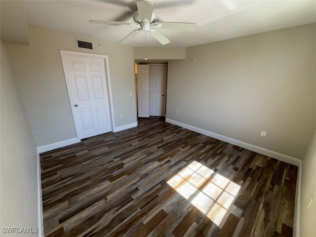 unfurnished bedroom with dark wood-style flooring, baseboards, visible vents, a ceiling fan, and a closet