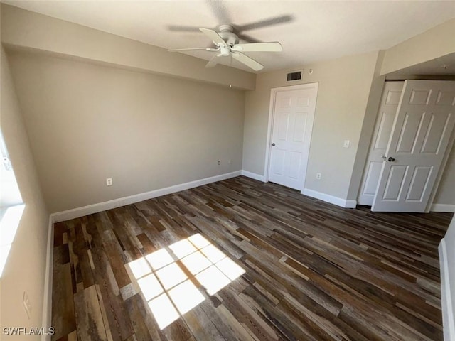 unfurnished bedroom with a ceiling fan, dark wood-type flooring, baseboards, and visible vents