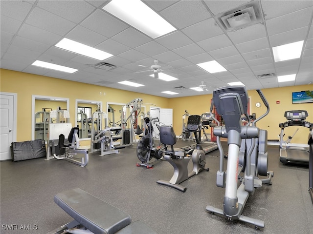 exercise room with ceiling fan and a drop ceiling