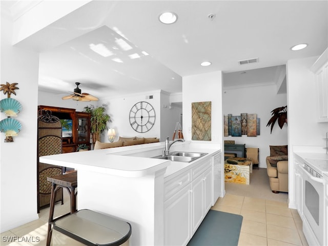 kitchen with sink, electric range, white cabinets, and a kitchen bar