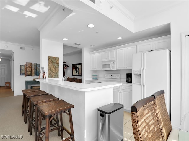 kitchen with white cabinets, a kitchen breakfast bar, ornamental molding, kitchen peninsula, and white appliances