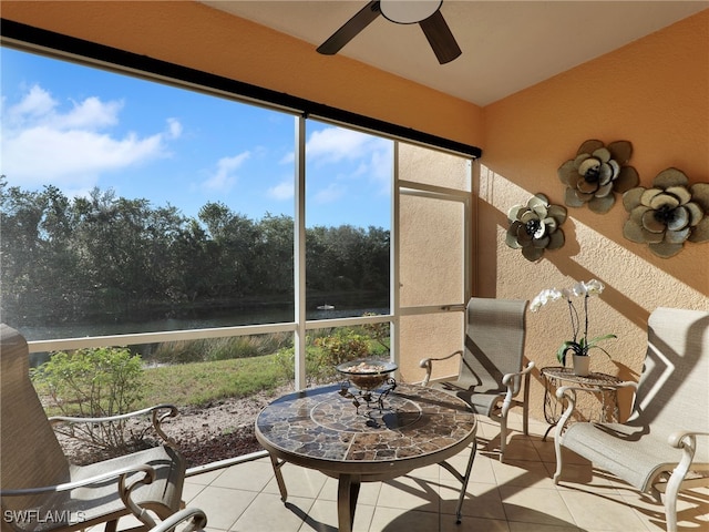 sunroom / solarium featuring ceiling fan and a water view