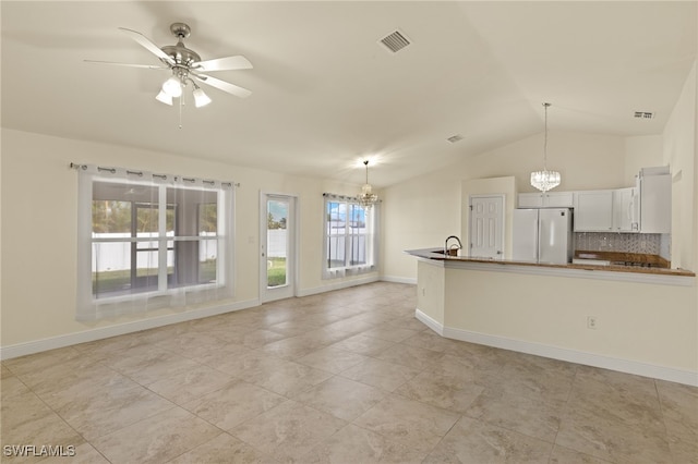 unfurnished living room featuring lofted ceiling, sink, and ceiling fan with notable chandelier